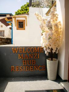 a vase filled with white flowers next to a sign at Manzi Hub Residence in Zanzibar City