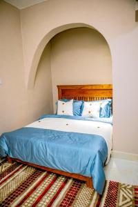a bedroom with a large bed with blue sheets and pillows at Manzi Hub Residence in Zanzibar City