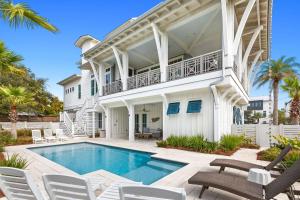 a white house with a swimming pool and chairs at Pomp in Paradise in Inlet Beach