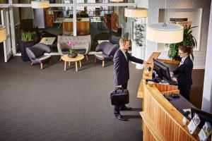 deux personnes debout à un bureau dans un bureau dans l'établissement Frederiksdal Sinatur Hotel & Konference, à Kongens Lyngby