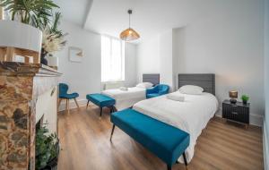 two beds in a room with blue chairs and a fireplace at Place Carnot in Tournus