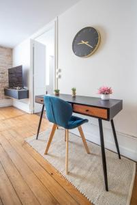 a desk with a blue chair and a clock on a wall at Place Carnot in Tournus