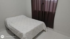 a white bed in a room with a curtain at Casa Proxima do Centro in Primavera do Leste