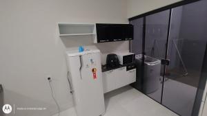 a small kitchen with a refrigerator and a microwave at Casa Proxima do Centro in Primavera do Leste