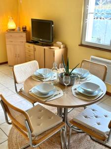 einen Esstisch mit Stühlen und einen TV in der Unterkunft Domaine Wagenbourg à Soultzmatt in Soultzmatt