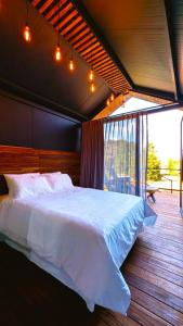 ein Schlafzimmer mit einem weißen Bett und einem Balkon in der Unterkunft DenHills in Denxhi