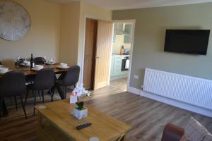 a living room with a table and a clock on the wall at Royal Oak Apartment in Brewood