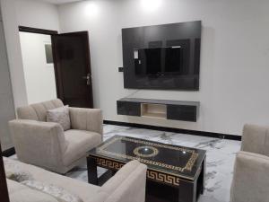 a living room with a tv and chairs and a table at Royal Apartments-One Bed Apartments in Islamabad