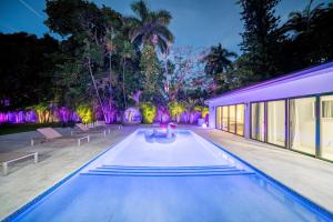 Una piscina con luces moradas en una casa. en Two Neighboring Villas in The Heart of Miami, en Golden Glades