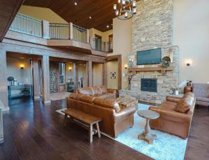 a living room with leather furniture and a stone fireplace at Spring Shores Lodge - Luxury Mountain Experience! in Ashton