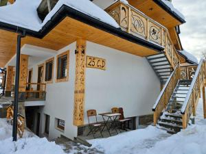 ein Haus im Schnee mit einem Tisch und Stühlen in der Unterkunft Apartament Bukowy by Domki Tatry in Bukowina Tatrzańska