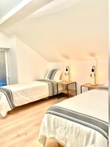 2 Betten in einem Zimmer mit weißen Wänden und Holzböden in der Unterkunft Maison Villa Foch in Meaux