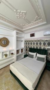 Schlafzimmer mit einem großen weißen Bett und einer Decke in der Unterkunft Riad dar Benaarab 2 aéroport 800 M in Marrakesch