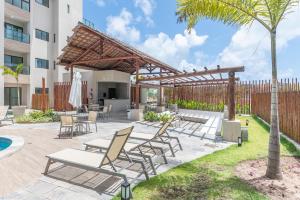 a patio with chairs and a wooden pergola at Max Carneiros Suítes - Conforto e sofisticação há alguns passos do mar! in Tamandaré