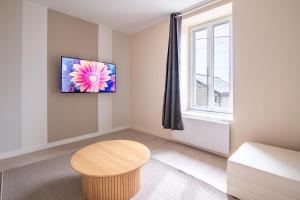 ein Wohnzimmer mit einem Tisch und einem Fenster in der Unterkunft La Parenthèse - Proche Puy du Fo u - 2 appartements équipés et confortables au coeur des Herbiers in Les Herbiers