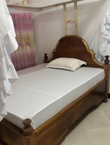 een bed met een houten hoofdeinde in een kamer bij Кокосовый домик in Nungwi