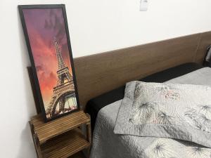 a picture of the eiffel tower next to a bed at Havana Flats - Apto térreo 700m praia - Área Gourmet com 3 churrasqueiras in Balneário Gaivotas