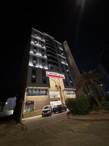 Un edificio con dos coches aparcados delante. en فندق التوحيد بارك 1 توصيل مجاني للحرم, en Al ‘Azīzīyah