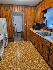 a kitchen with wooden cabinets and a sink and a refrigerator at Macon Duplex Getaway | 3BR, WiFi, BBQ & Parking in Riverside Park
