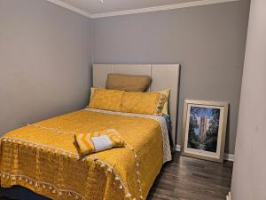 a bedroom with a bed with a yellow blanket and a picture at Macon Duplex Getaway | 3BR, WiFi, BBQ & Parking in Riverside Park