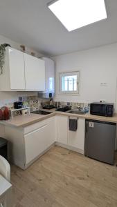 a large kitchen with white cabinets and a window at Le Plein Sud - Carqueiranne in Carqueiranne
