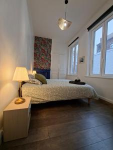 Un dormitorio con una cama con una lámpara y una ventana. en L'elegant hyper centre, en Dunkerque