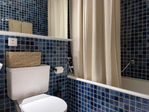 a blue tiled bathroom with a toilet and a shower at Retro Alpine Studio - Terrace with Mountain View in Leukerbad +17 photos