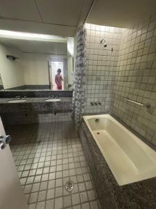 un bagno con vasca e una persona in uno specchio di Bugan Paiva flatpaivahome a Recife