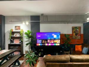 a living room with a couch and a flat screen tv at Warm & Luxury Stay at Maboneng with Kingbed HugeTV WiFi in Johannesburg