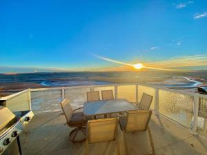 a table and chairs on a balcony with the sunset at Covington Close in Calgary