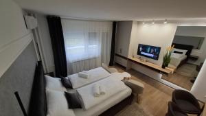 ein Wohnzimmer mit einem weißen Sofa und einem Fernseher in der Unterkunft Studio apartman OAZA in Vukovar