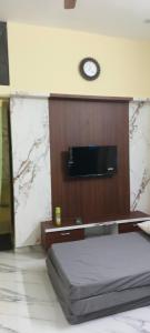 a room with a bed and a clock on the wall at AKR Homestay in Tiruvannāmalai +2 photos