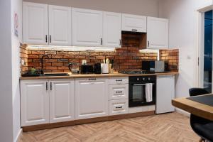 a kitchen with white cabinets and a brick wall at Lusia Apartment in Jarosław