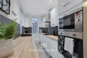 eine Küche mit weißen Schränken und einer Pflanze in einem Topf in der Unterkunft Stylish 4BR South Shields Home - Contractors & Family Stay in Westoe
