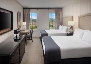 a hotel room with two beds and a desk and a television at The Inn at Patrick Square in Clemson