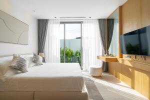 a hotel room with a bed and a television at Botanica Aroon Luxury Pool Villa 3 BR Lagoona Bangtao beach in Ban Pak Lak +30 photos