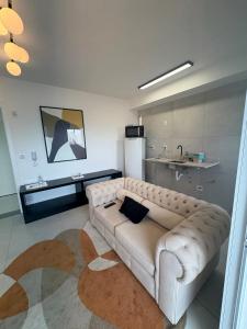 a living room with a white couch and a kitchen at Red Building Apartment in Bauru