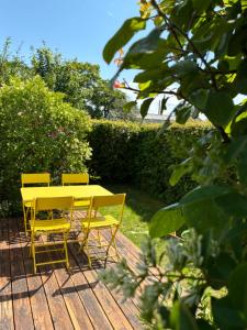 un tavolo giallo e sedie su una terrazza in legno di Maison de campagne au bord de la mer a Fort-Mahon-Plage