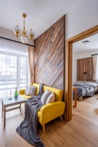 ein Wohnzimmer mit einer gelben Couch und einem Bett in der Unterkunft Chata Vermont in Bedřichov
