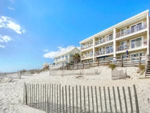 ein Gebäude am Strand mit einem Zaun davor in der Unterkunft Leeward II 3 l Beachfront Condo l Large first level deck with steps down to sand in Watersound Beach + 16 Fotos