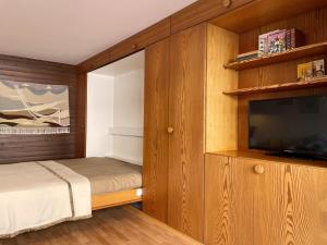 a bedroom with a bed and a flat screen tv at Retro Alpine Studio - Terrace with Mountain View in Leukerbad
