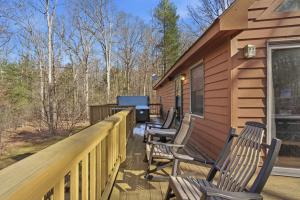 a deck with chairs and a grill on a cabin at Family-Friendly Home w Hot Tub Fire Pit Games in North Glade