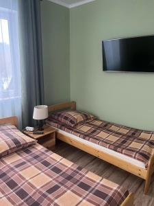 2 Betten in einem Zimmer mit einem TV an der Wand in der Unterkunft Pokoje Gościnne in Ujsoły + 33 Fotos