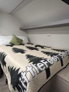 een bed met een zwart-wit dekbed erop bij Little Foot RV in Klamath