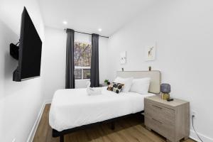 una camera da letto bianca con un letto e una TV di Downtown Penthouse 2 Level-4BDRS-8Guests a Montréal