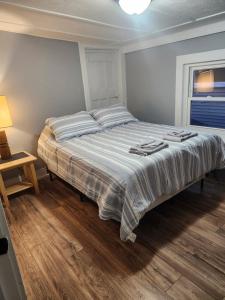 a large bed in a bedroom with a lamp on a wooden floor at Central Apartment, Steps from the Park in Oswego