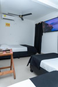 a room with two beds and a tv and a table at Neos Hotel Cartagena in Cartagena de Indias