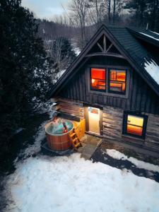 a hot tub in front of a cabin in the snow at Boutique Log Cabin & Two Guest Cabins, Hot Tub, Sauna, Swimming Hole, near Whiteface in Upper Jay