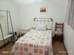 a bedroom with a bed with a quilt and a chair at La casita in Medellín