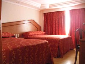 a hotel room with two beds and red curtains at Hotel Premier in Mexico City
